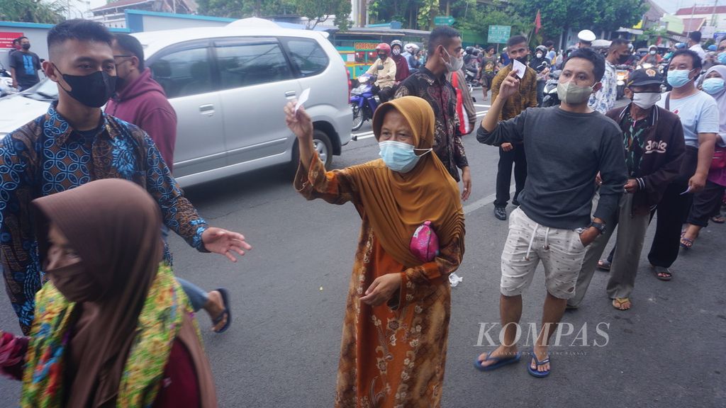 Para warga menunjukkan kupon untuk mengambil bantuan dari Presiden Joko Widodo yang dibagikan di Pasar Serangan, Yogyakarta, Jumat (1/5/2022). Total ada 1.200 paket bantuan yang dibagikan. Warga antusias menyambut pembagian bantuan berisi bahan pokok tersebut.