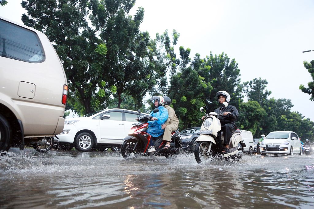 Pengendara melewati genangan air di Jalan Tanjung Barat, Jagakarsa, Jakarta Selatan, Sabtu (3/12/2022). Air setinggi 20 sentimeter mengakibatkan kendaraan yang melintas harus menurunkan kecepatannya. Hal tersebut berdampak munculnya kemacetan panjang, mulai dari Jalan Raya Pasar Minggu sampai depan Aeon Mall.