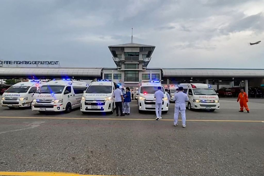 The photo taken from a video footage on May 21, 2024 shows an airplane taking off while medical staff gather near an ambulance at Suvarnabhumi Airport in Bangkok, Thailand. A Singapore Airlines plane made an emergency landing at the airport due to severe turbulence.