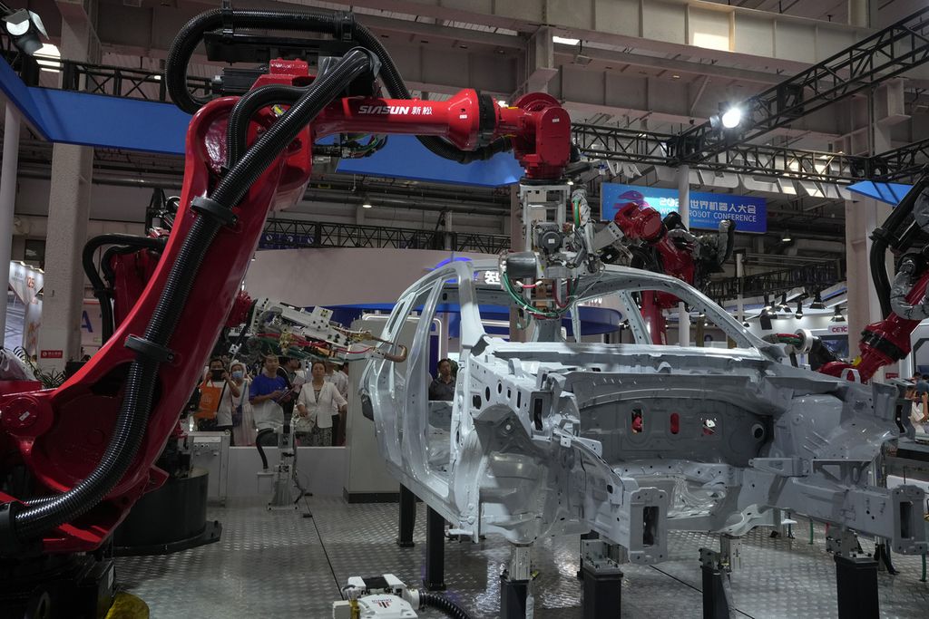 Pengunjung melihat lengan robotik merakit sebuah rangka mobil saat Konferensi Robot Dunia di Beijing, China, 17 Agustus 2023. 