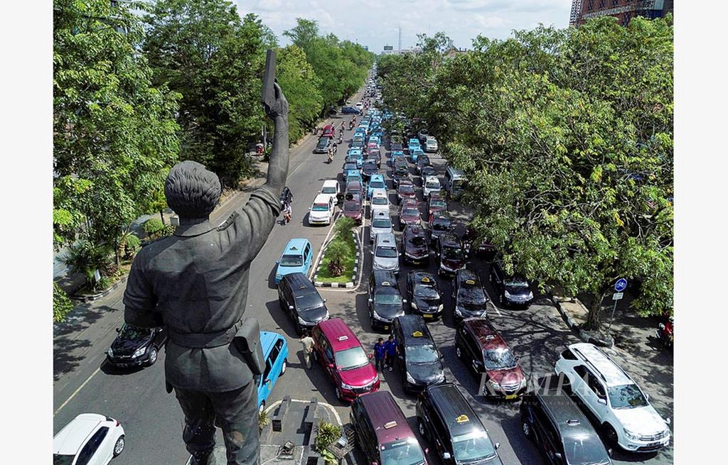 Sopir taksi memarkir kendaraan mereka di kawasan Bundaran Gladak, Kota Solo, Jawa Tengah, saat mengikuti aksi mogok, Selasa (11/7). Aksi itu untuk menuntut Pemerintah Kota Solo menindak tegas pengoperasian  taksi berbasis daring.