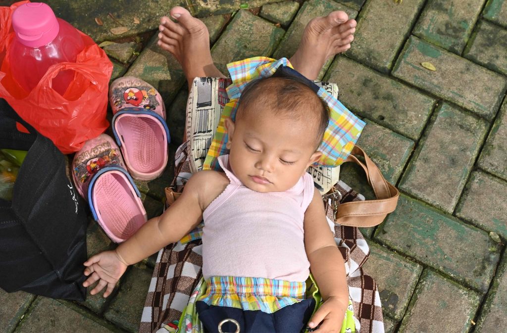 Seorang bayi tampak tidur terlelap di pangkuan ibunya di sebuah tempat bermain di Jakarta, 29 Maret 2022.