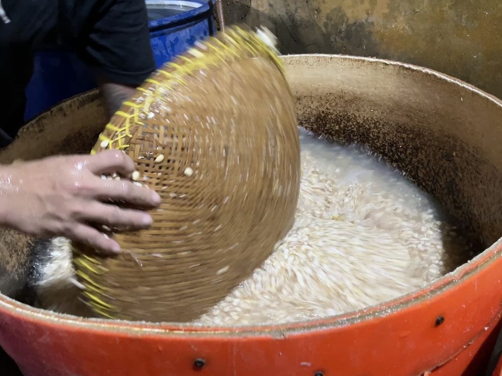 Perajin tempe mengaduk kedelai agar tercampur dengan ragi dalam proses pembuatan tempe di di Johar Baru, Jakarta Pusat, Jumat (14/10/2022). Perajin tempe mendesak pemerintah untuk segera mengendalikan harga kedelai.