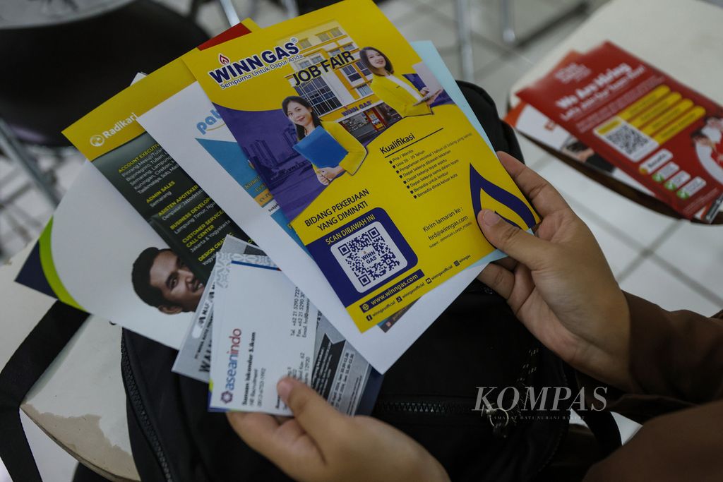 Tangan pencari kerja memegang brosur lowongan kerja di acara<i> job fair</i> di Universitas Tama Jagakarsa, Jakarta Selatan, Selasa (25/4/2024). 