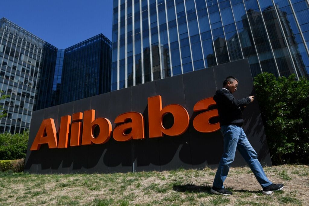 Seorang pria berjalan melewati logo Alibaba di luar kantor perusahaan di Beijing, China, pada 13 April 2021.
