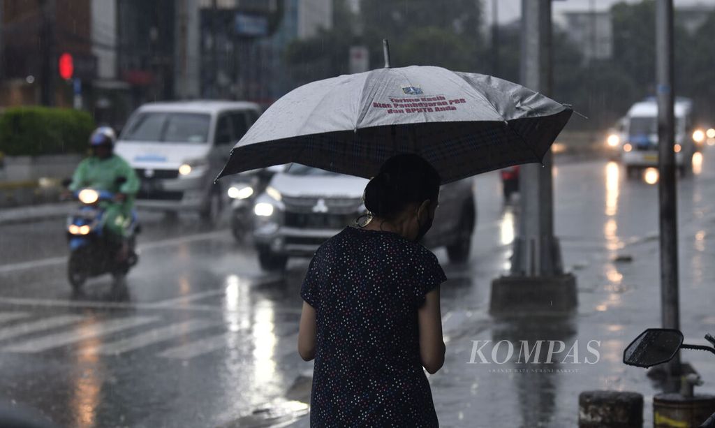 Warga memakai payung di tengah hujan deras yang turun di kawasan Petojo, Jakarta Pusat, Selasa (4/10/2022). 