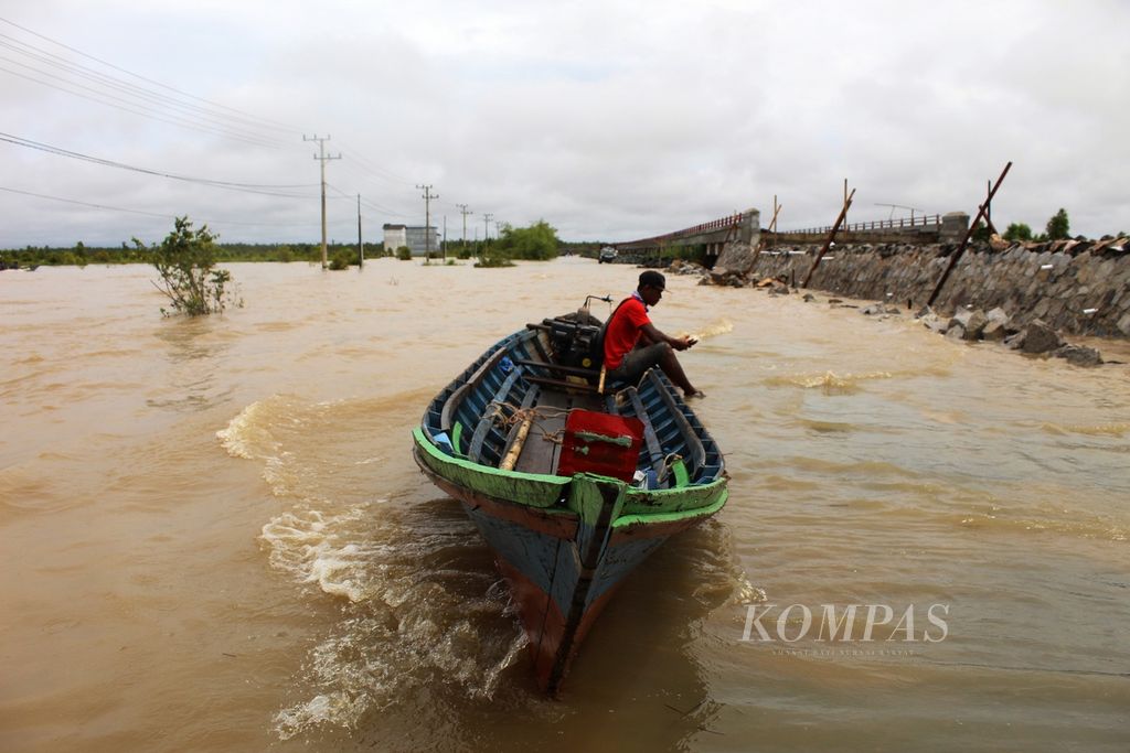 Pemilik perahu kayu bermesin atau yang biasa disebut kelotok menunggu penumpang di tengah banjir Desa Penda Barania, Bukit Rawi, Kabupaten Pulang Pisau, Kalteng, Minggu (14/11/2021). Jalur Trans-Kalimantan itu sudah terendam banjir setidaknya tiga hari. Jalur pun terputus.