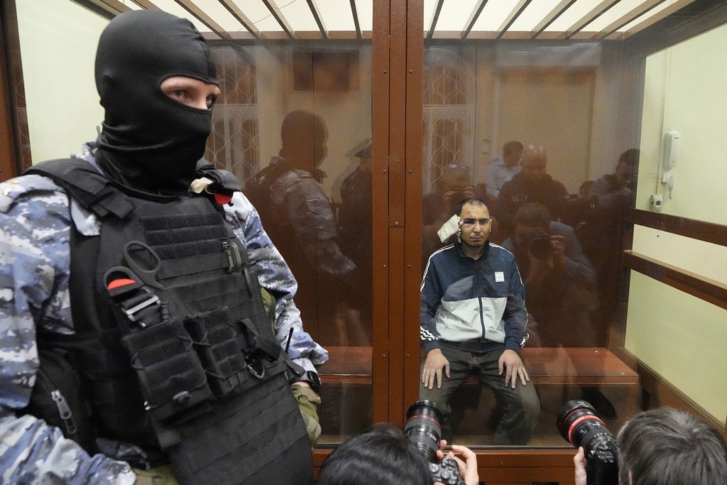 Aparat keamanan Rusia menjaga Saidakrami Murodali Rachabalizoda, salah satu terduga pelaku penembakan di Balai Kota Crocus di Moskwa, Rusia, saat menjalani sidang awal di Pengadilan Distrik Basmanny, Moskwa, Minggu (24/3/2024). 