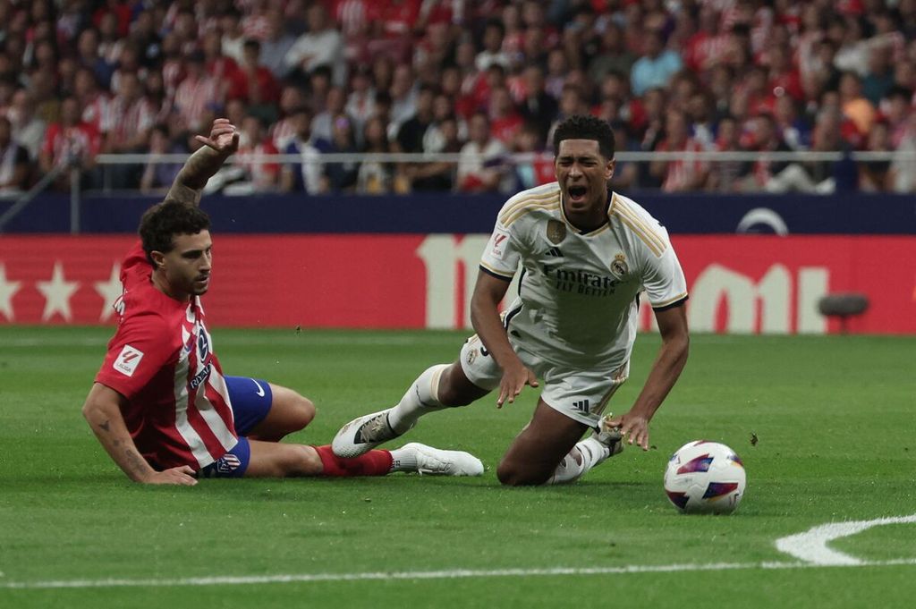Bek Atletico Madrid Mario Hermoso (kiri) menekel penyerang Real Madrid Jude Bellingham pada laga Liga Spanyol di Stadion Metropolitano, Senin (25/9/2023) dini hari WIB. Atletico menang, 3-1.