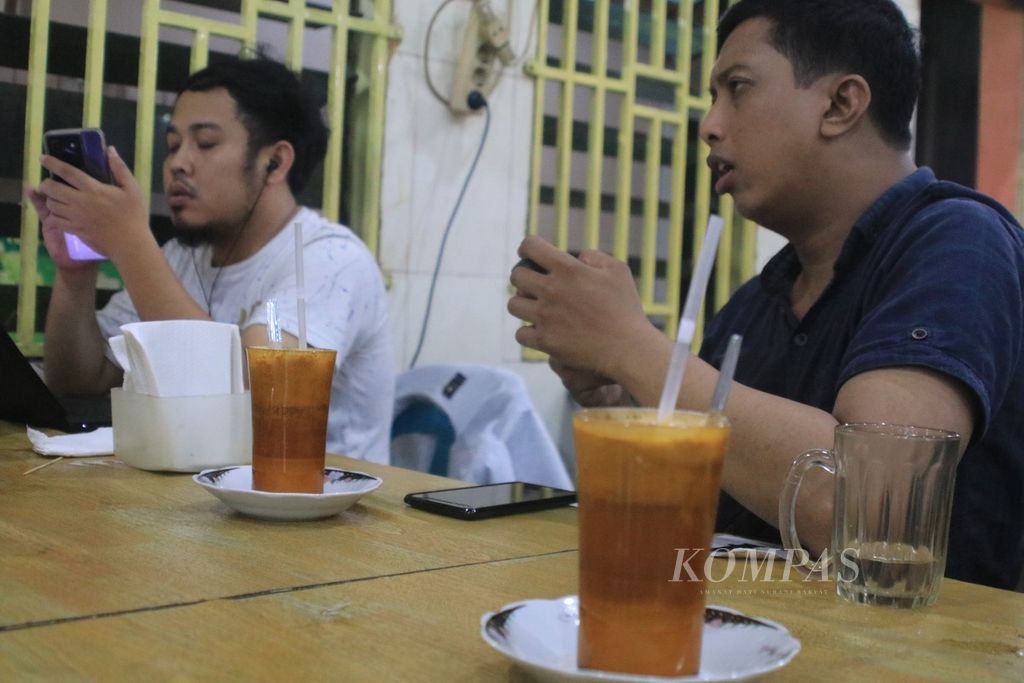Pengunjung menikmati minuman teh susu telur (TST) di Warung TST Pak Haji di Jalan Puri, Medan, Sumatera Utara, Jumat (3/11/2023). 