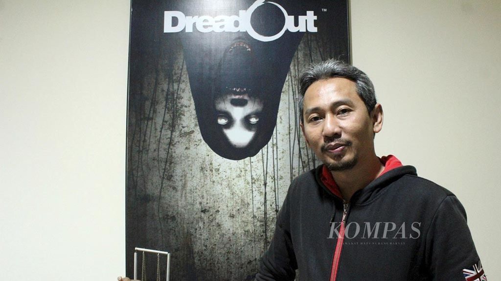 Rachmad Imron, CEO Digital Happiness, berfoto dengan latar poster gim bergenre horor DreadOut, Kamis (9/5/2019).
