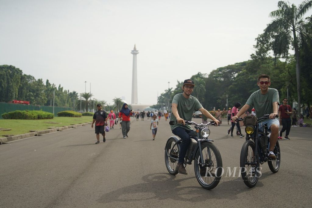 Pendiri Vintage Electric Bikes, Andrew Davidge (kiri), berpose dengan salah seorang pemilik sepeda listrik buatannya tersebut di kawasan Monas, Jakarta, Minggu (9/10/2022). 