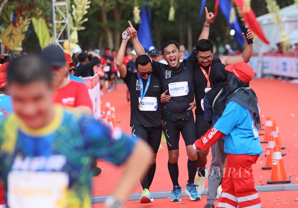 Dua peserta yang sudah menerima medali membantu rekan sesama pelari yang mengalami kram kaki untuk melintasi garis finis dalam Borobudur Marathon 2023 Powered by Bank Jateng di Taman Lumbini, Borobudur, Jawa Tengah, Minggu (19/11/2023). 