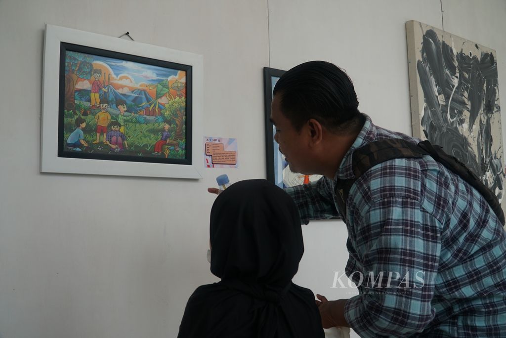Pengunjung mendampingi putrinya mengamati lukisan karya anak-anak yang dipamerkan dalam Festival Anak Sumatera Barat 2023 yang diadakan Dinas Pemberdayaan Perempuan dan Perlindungan Anak, Pengendalian Penduduk, dan Keluarga Berencana Sumbar di Istana Gubernur Sumbar, Kota Padang, Sumbar, Sabtu (18/11/2023). 