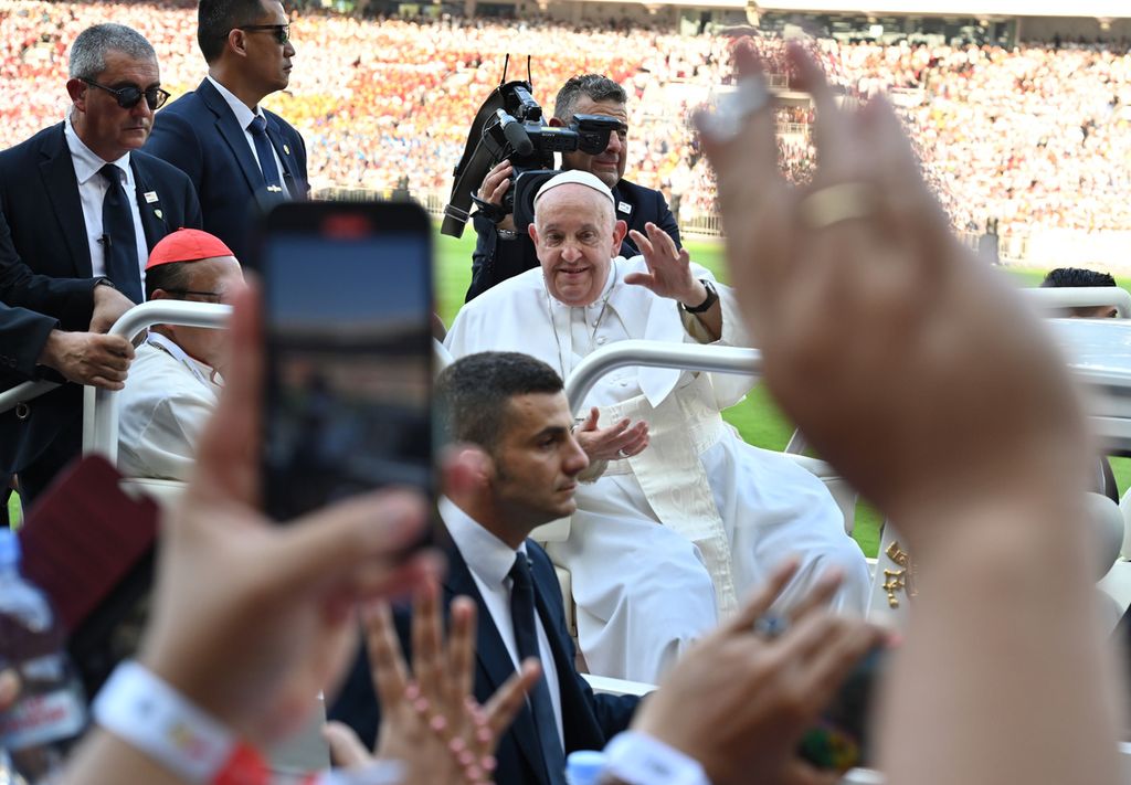 Paus Fransiskus menyapa umat Katolik yang hadir memenuhi Stadion Utama Gelora Bung Karno (GBK), Jakarta, sebelum dimulainya perayaan ekaristi, Kamis (5/9/2024). Paus Fransiskus naik mobil buatan Pindad, &quot;Maung&quot;, untuk berkeliling stadion dan menyapa umat. Selain di GBK, Paus juga menyapa umat yang berada di Stadion Madya GBK.