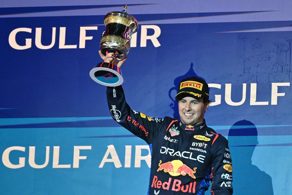 Pebalap Red Bull Racing, Sergio Perez, mengangkat trofi setelah meraih podium kedua dalam balapan pembuka Grand Prix Formula 1 2024 di Sirkuit Internasional Bahrain. Sabtu (2/3/2024). Max Verstappen dari tim Red Bull Racing berhasil meraih podium pertama. 