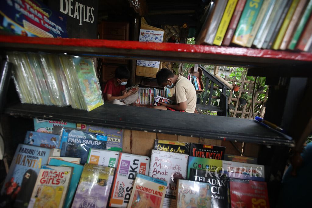 Anak-anak membaca buku di Bale Buku di Kelurahan Dukuh, Kramat Jati, Jakarta Timur, 15 Januari 2022. Bale ini dibuat dari barang-barang bekas oleh Komunitas Baca Bale Buku.  