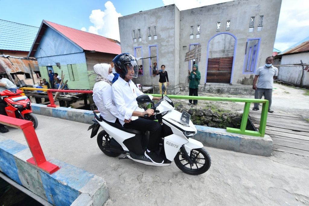 Presiden Joko Widodo memboncengkan Nyonya Iriana dengan sepeda motor listrik yang digunakan untuk menuju lokasi penyerahan sertifikat di Kampung Mola, Pulau Wangi-wangi, Kabupaten Wakatobi, Provinsi Sulawesi Tenggara, Kamis (9/6/2022). 
