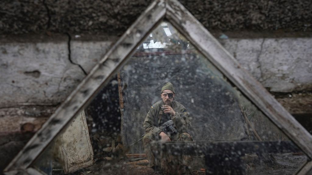 Refleksi wajah seorang anggota militer Ukraina yang tengah berjaga di posnya di dekat Zolote, Ukraina, Sabtu (19/2/2022). Selang sepekan kemudian, Rusia menginvasi Ukraina. 