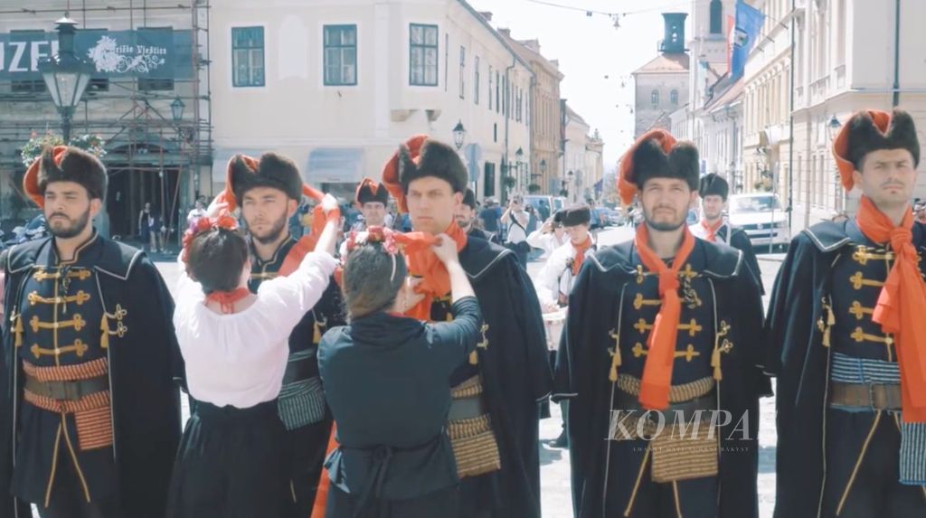 Dalam tangkapan layar dari video yang disiarkan pada Mei 2017 ini, warga Zagreb, Serbia mengikuti pawai dengan mengenakan busana anggota resimen Cravat. Pada abad 17, resimen itu dikenal pula sebagai Resimen Kroasia karena seluruh anggotanya dari Kroasia. Resimen itu salah satu kelompok tentara bayaran dalam berbagai perang di Eropa.