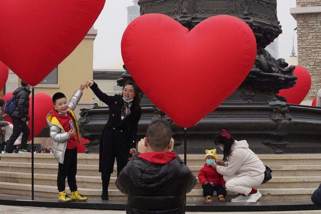 Satu keluarga berpose untuk berfoto di dekat dekorasi berbentuk hati di pusat kota Beijing, China.