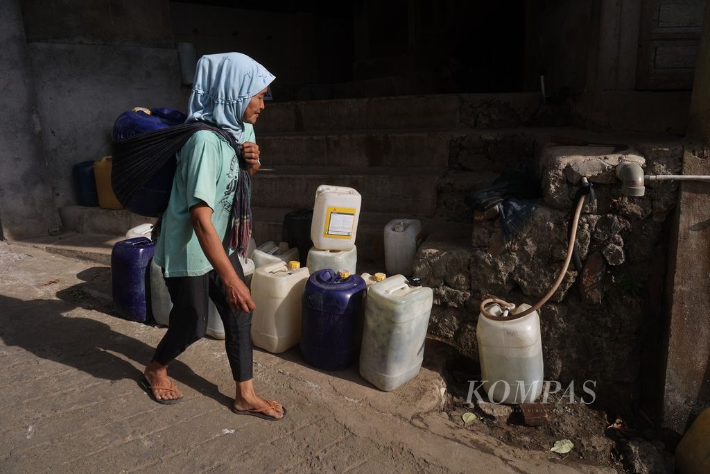 Kartinah (54) carried a jerican filled with water taken from a spring in Dusun Butuh, Candirejo Village, Borobudur District, Magelang Regency, Central Java on Tuesday (3/9/2023). Residents in the village were experiencing a drought and had to fetch water from outside the village.