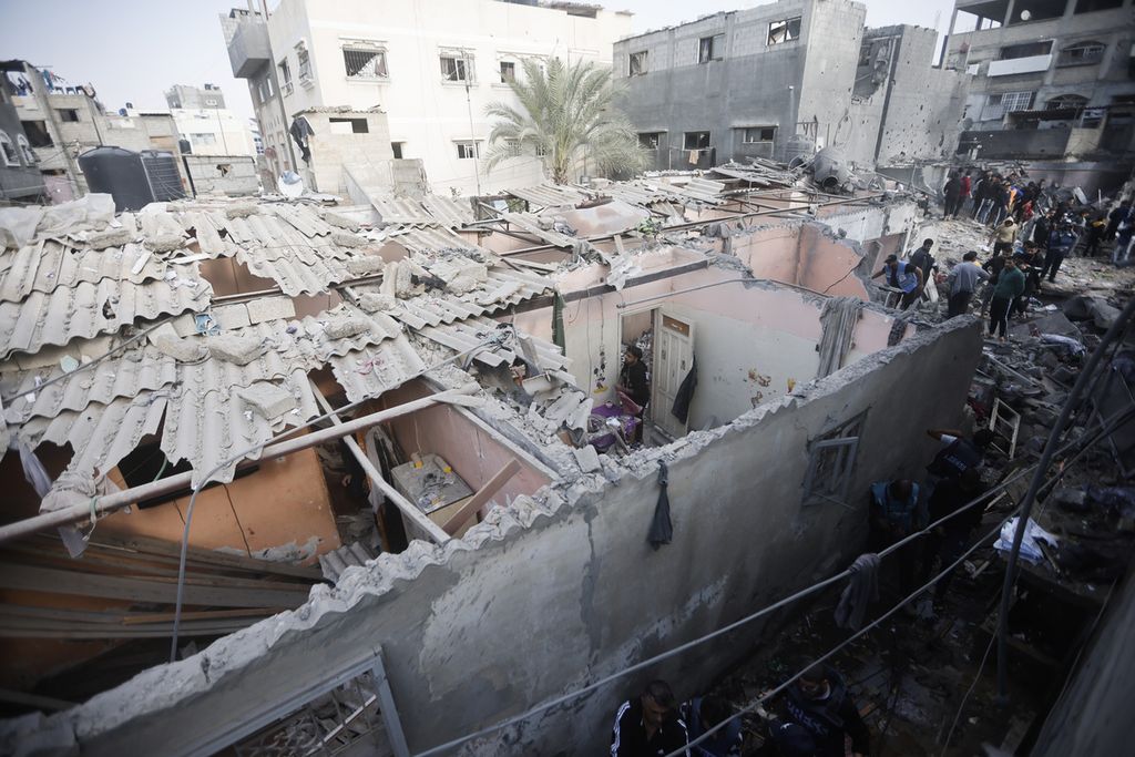 Warga Palestina melihat bangunan yang hancur akibat serangan militer Israel di kamp pengungsi di Khan Younis,  Jalur Gaza, 1 Desember 2023. 