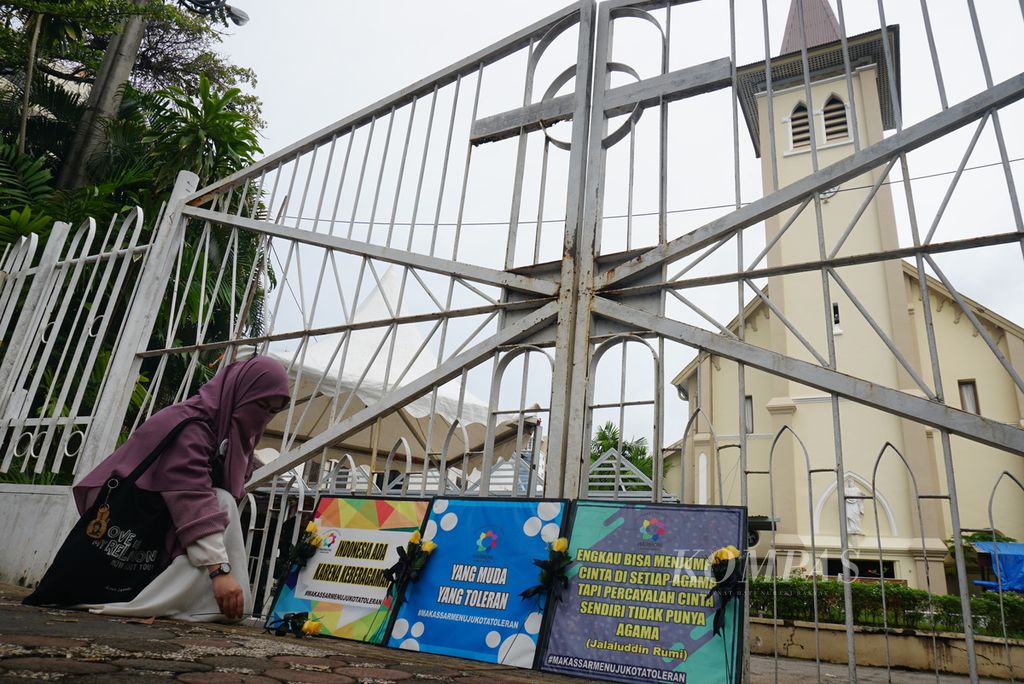 Seorang peserta aksi solidaritas antarumat beragama memungut bunga untuk ditata di depan Katedral Hati Yesus yang Mahakudus, Makassar, Sulawesi Selatan, pada perayaan Minggu Paskah, Minggu (4/4/2021). Aksi itu adalah respons terhadap serangan teror bom bunuh diri yang terjadi pekan lalu.