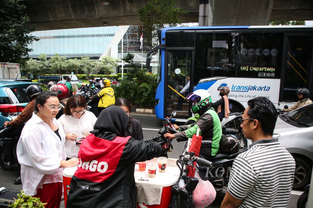 Karyawan membeli kopi dari pedagang keliling di kawasan Kuningan, Jakarta Selatan, saat jam makan siang, Selasa (27/2/2024). Kemampuan komunikasi menjadi hal yang paling utama dalam peningkatan karier karyawan.
