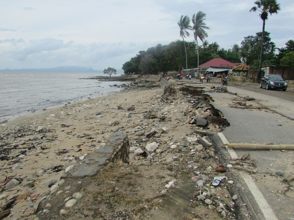 Tanggul pembatas jalan di Kelurahan Oesapa, tepatnya dari arah pantai Lasiana menuju Pasar Oesapa, jebol diterjang gelombang. Tampak pula badan jalan berupa aspal sebagian ambruk karena gelombang.