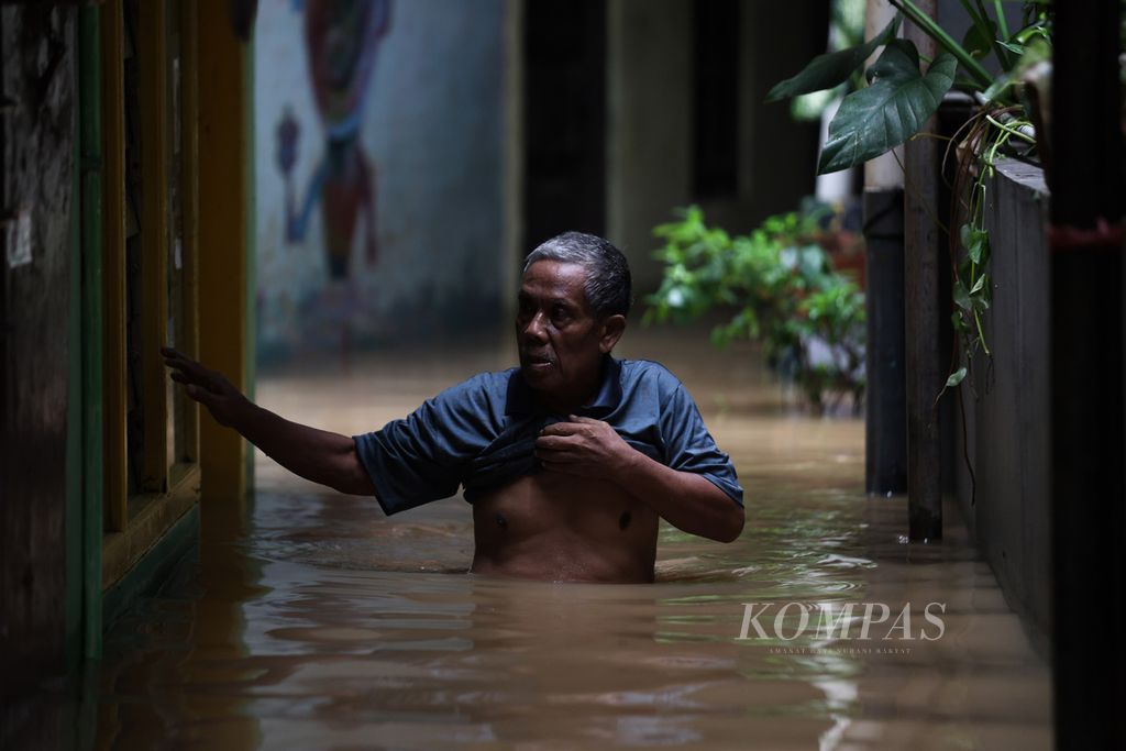 Seorang warga berusaha melewati banjir di Kelurahan Kampung Melayu, Kecamatan Jatinegara, Jakarta Timur, Kamis (30/11/2023).