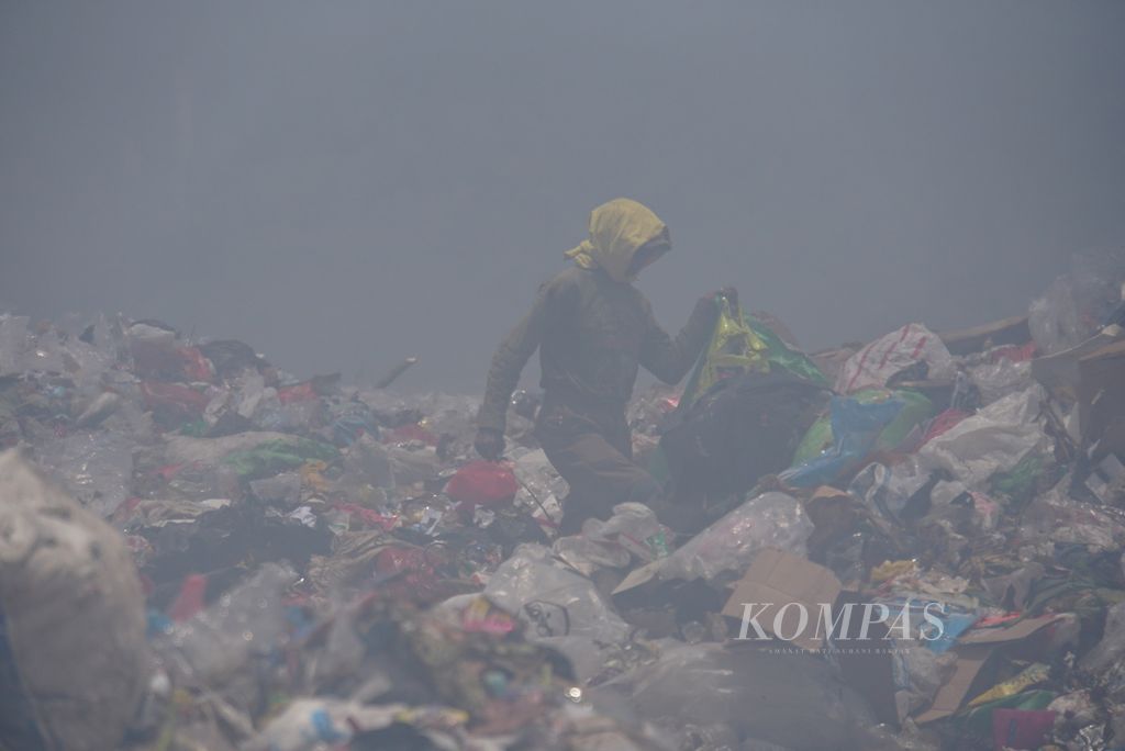 Seorang pemungut sampah tetap bekerja di tengah kepungan kabut asap yang menyelimuti Tempat Pembuangan Akhir (TPA) Sumompo di daerah Tuminting, Manado, Sulawesi Utara, pada Rabu (4/10/2023).