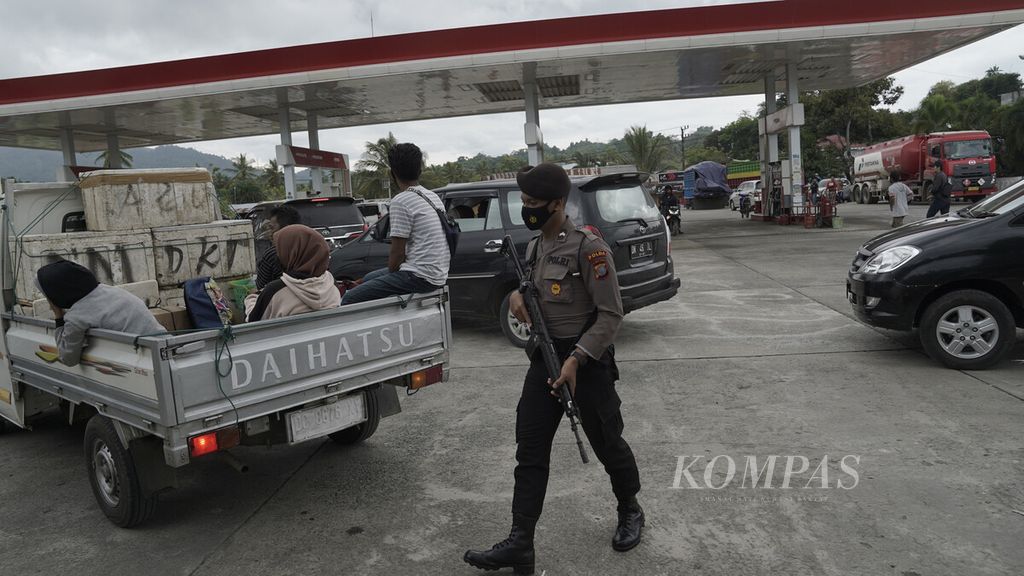 Polisi berjaga dalam antrean pengisian bahan bakar minyak di Mamuju, Sulawesi Barat, Minggu (17/1/2021).
