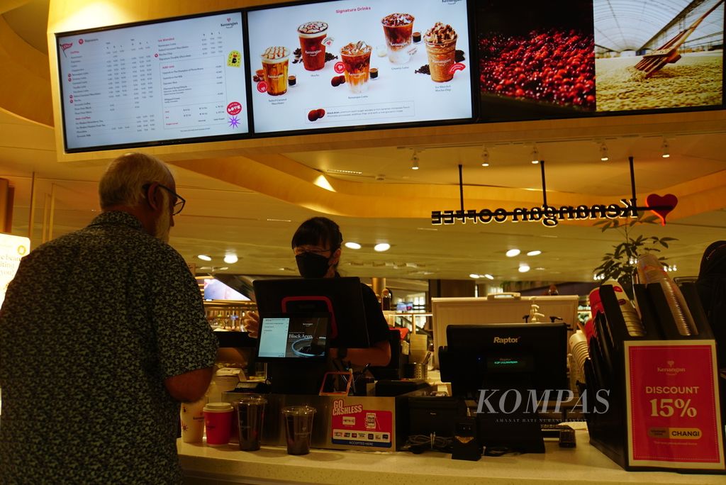 Barista melayani pelanggan di konter gerai kedua Kenangan Coffee di Singapura yang dibuka di Terminal 2 Bandara Changi, Selasa (26/9/2023).