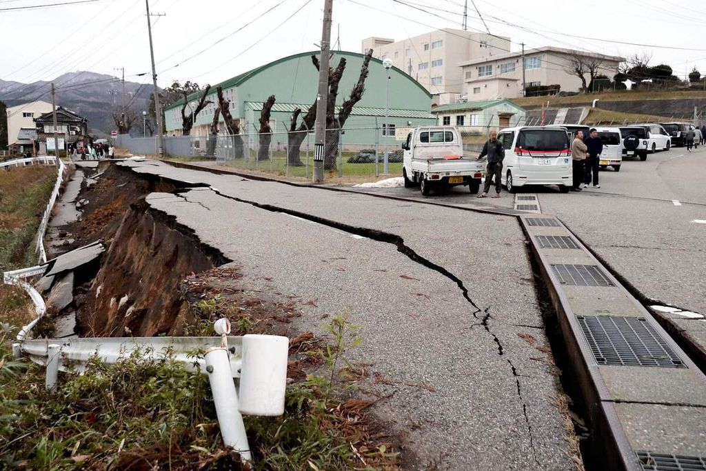 Warga di kota Wajima, Prefektur Ishikawa, melihat rekahan lebar di permukaan tanah pascagempa berkekuatan M 7,5, Senin (1/1/2024). 