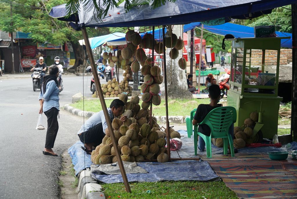Pedagang memilihkan durian untuk pembeli di salah satu lapak di pinggir Jalan Dr Wahidin, Kelurahan Gantiang Parak Gadang, Kecamatan Padang Timur, Padang, Sumatera Barat, Sabtu (7/8/2021) sore. Inflasi yang tinggi di Sumbar lebih dirasakan masyarakat kecil.