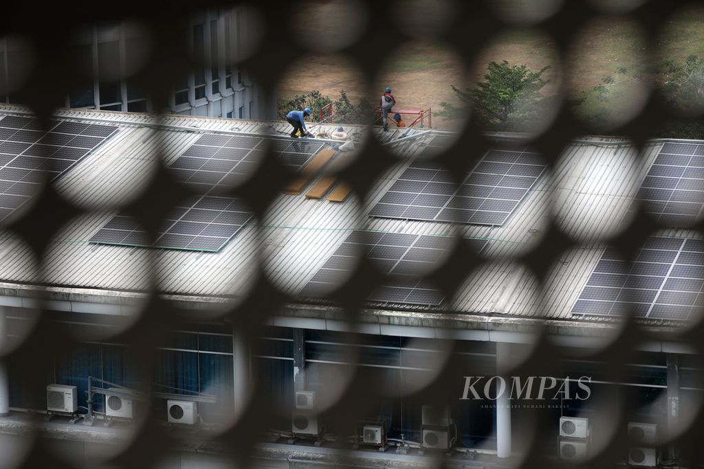 Pekerja berada di atap bangunan yang penuh dengan panel surya di Kampus Universitas Multimedia Nusantara, Kabupaten Tangerang, Banten, Rabu (20/9/2023). Kampus UMN tengah memasang instalasi panel surya sebagai alternatif sumber energi listrik baru dan terbarukan. 
