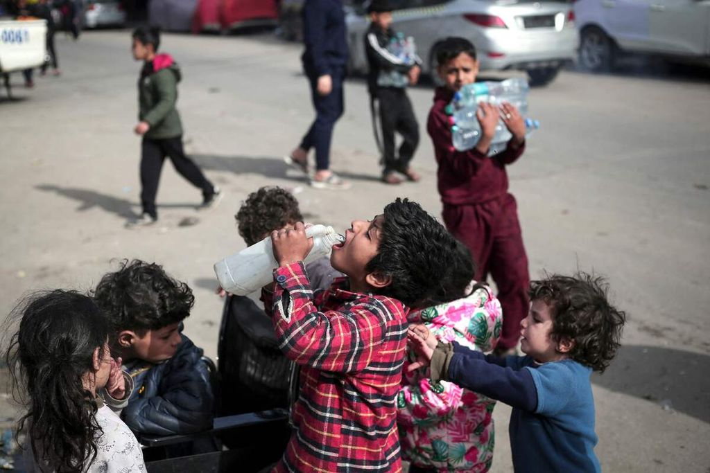 Anak-anak Palestina minum air di Rafah, Jalur Gaza bagian selatan, di tengah pertempuran yang terus berkobar antara kelompok Hamas dan militer Israel, 1 Maret 2024. 