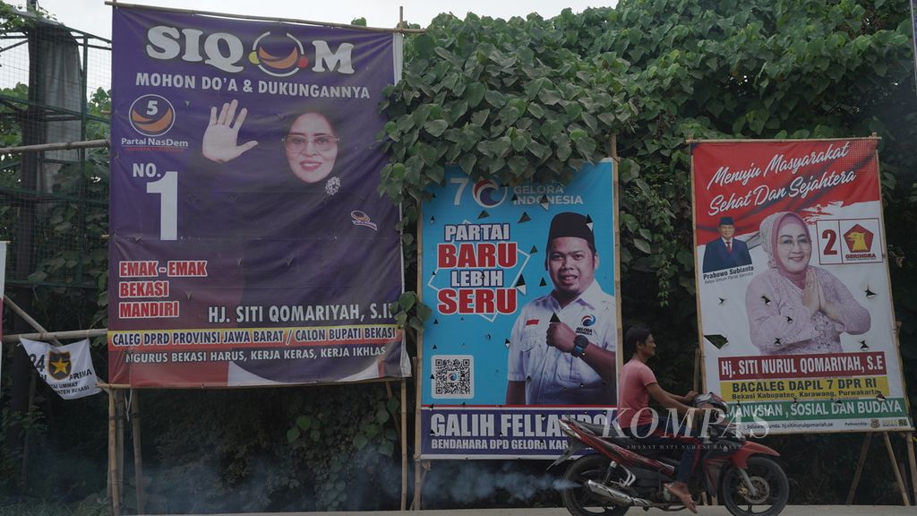 Warga melintasi spanduk bergambar bakal calon anggota legislatif di Babelan, Kabupaten Bekasi, Jawa Barat, Senin (24/7/2023). 