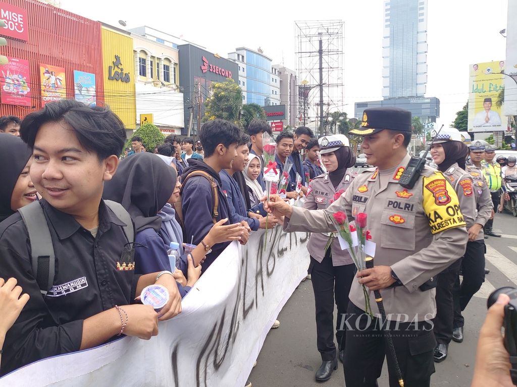 Aparat kepolisian dari Polresta Bandar Lampung membagikan bunga kepada para demonstran saat aksi peringatan Hari Buruh Internasional di Bandar Lampung, Lampung, Rabu (1/5/2024). 