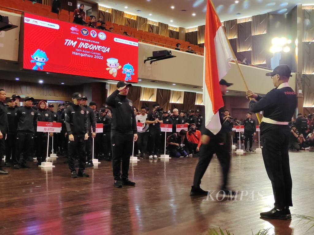 Atlet, pelatih, dan ofisial kontingen Indonesia untuk Asian Games Hangzhou, China 2022 mencium bendera seusai upacara pengukuhan kontingen di Kantor Kementerian Pekerjaan Umum dan Perumahan Rakyat, Jakarta, Selasa (19/9/2023). 