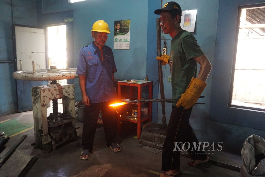 Muchlis, salah satu pandai besi, menyelesaikan pembuatan egrek atau alat pemanen kelapa sawit di sentra logam, Desa Pasir Wetan, Karanglewas, Banyumas, Jawa Tengah, Rabu (26/7/2023).