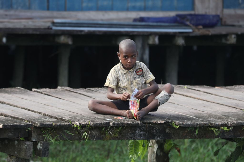 Seorang anak asyik memakan mie instan tanpa dimasak terlebih dahulu di kampung As, Distrik Pulau Tiga, Asmat, Papua, Jumat (15/10/2021).