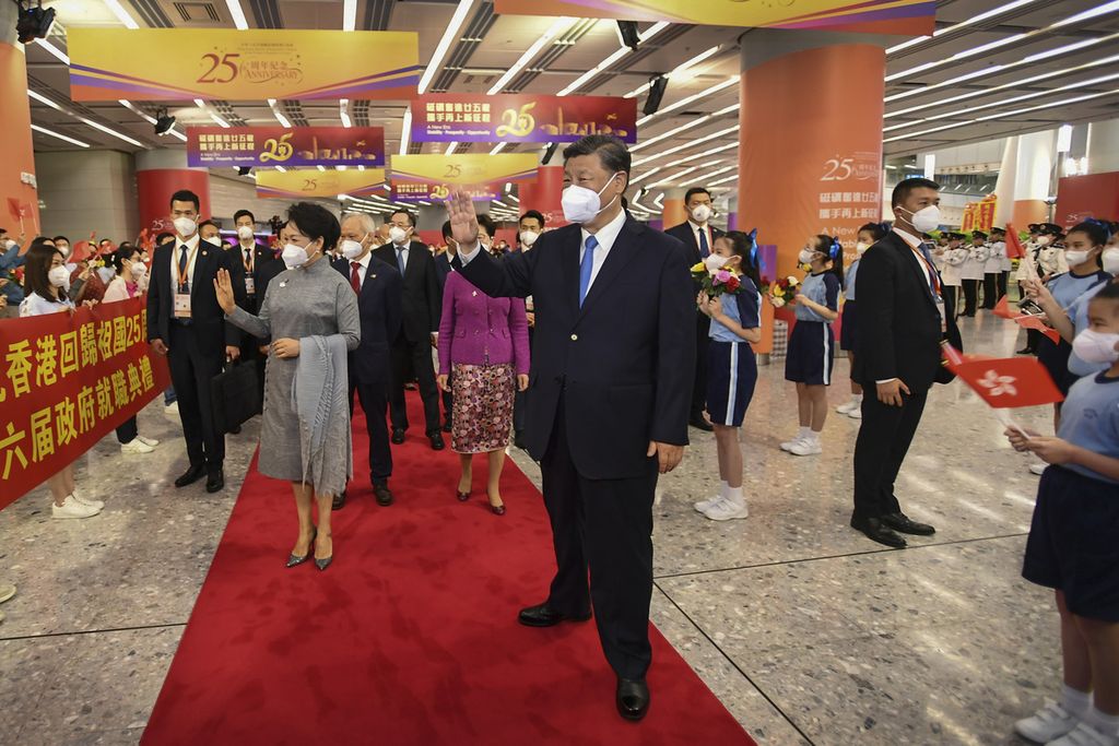 Presiden China Xi Jinping (tengah) dan istrinya, Peng Liyuan (tengah, kiri), melambaikan tangan ke arah kumpulan warga yang menyambut keduanya saat tiba di stasiun kereta di Hong Kong, 30 Juni 2022. 