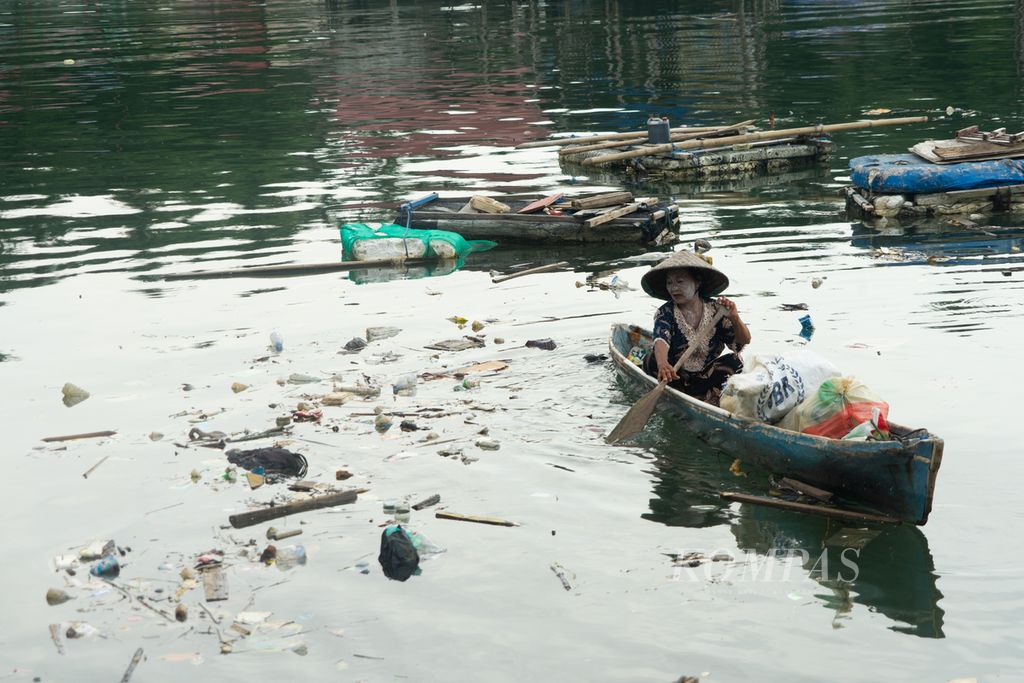 Hanafiah (60) memungut sampah plastik dari pesisir Teluk Kendari, Sulawesi Tenggara, Minggu (2/1/2022). Janda berusia lanjut ini bertahan hidup dengan memulung sampah plastik setiap hari. Ia dan sejumlah perempuan pemulung lainnya tidak mendapat bantuan dari pemerintah sama sekali meski berulang kali didata.