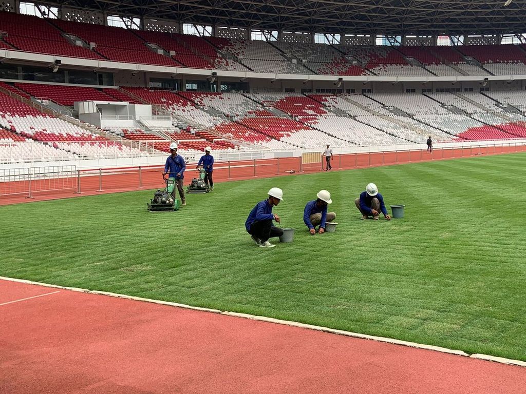 Sejumlah pekerja melakukan perawatan pada rumput baru lapangan Stadion Utama Gelora Bung Karno, Rabu (28/9/2022). Perbaikan lapangan telah berlangsung sejak Mei 2022 dan saat ini perkembangannya menyentuh 95 persen