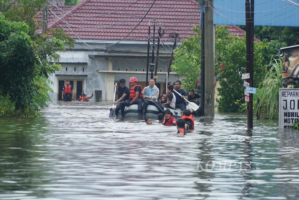 Petugas Dinas Damkar dan BPBD Kota Padang mengevakuasi warga yang terdampak banjir dengan perahu karet di Kelurahan Dadok Tunggul Hitam, Kecamatan Koto Tangah, Kota Padang, Sumatera Barat, Jumat (14/7/2023) pagi.