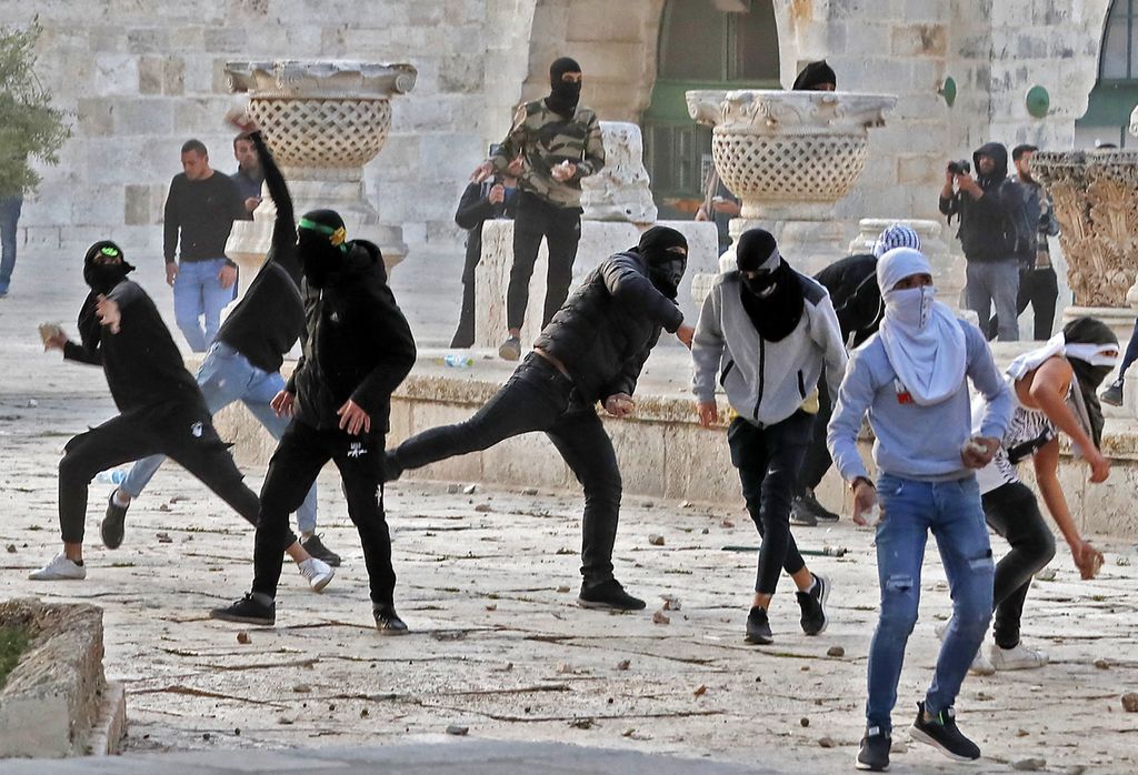 Sejumlah pemuda Palestina melempari aparat keamanan Israel dengan batu ketika kedua pihak bentrok, Jumat (22/4/2022). Liga Arab mengecam tindakan aparat keamanan Israel yang mengizinkan warga Yahudi beribadah di komplek Masjidil Aqsa sebagai tindakan yang provokatif dan ilegal. 