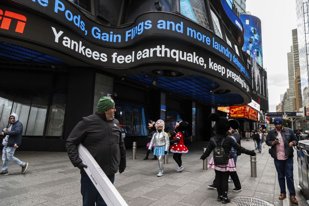 Sejumlah warga berjalan di depan gedung yang dilengkapi dengan layar di Times Square, New York, Amerika Serikat, 5 April 2024. Di layar, warga bisa melihat informasi soal gempa bermagnitudo 4,8 yang baru saja melanda kota itu. 