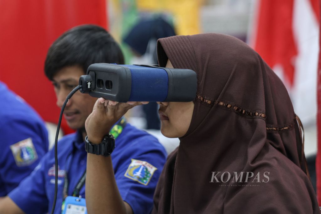 Petugas Dinas Kependudukan dan Pencatatan Sipil (Dukcapil) memasangkan alat perekam retina mata ke mata salah seorang siswi yang mengikuti perekaman KTP elektronik di SMAN 38 Jakarta, Rabu (7/2/2024).